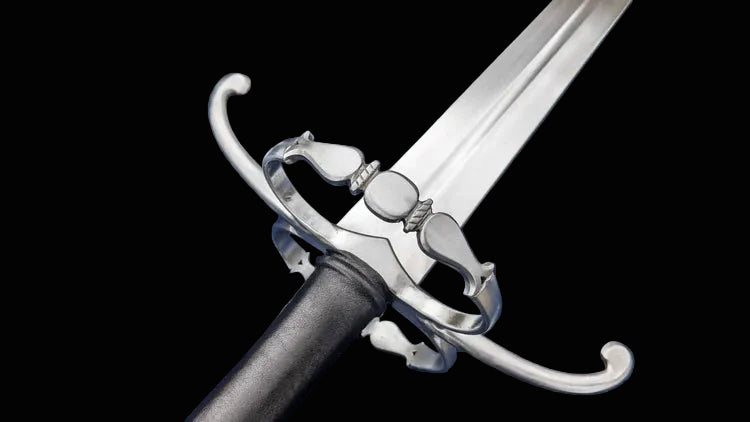A close-up of a medieval-style sword with a polished silver-colored steel blade, guard, and pommel, and a black grip