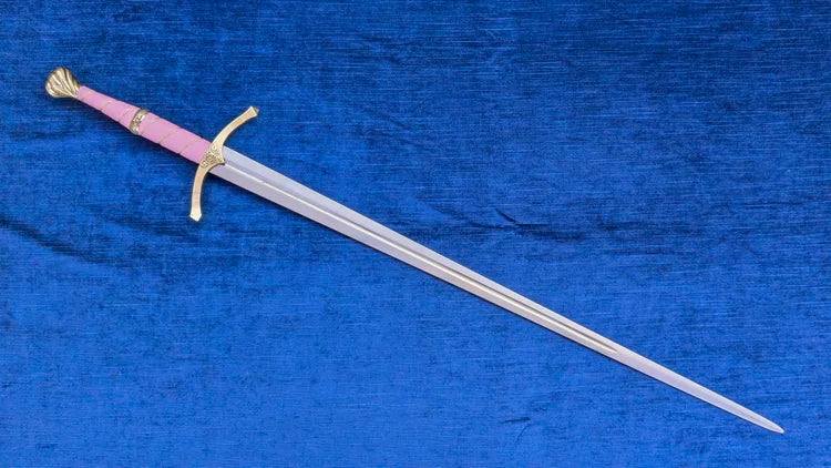A medieval-style sword with a pink grip and gold guard, displayed diagonally on a textured blue fabric background.