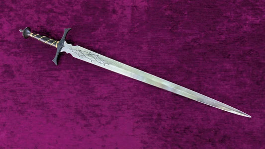 A decorative sword with an engraved silver blade, a black crossguard, and a gold-wrapped hilt, displayed diagonally on a textured purple background.
