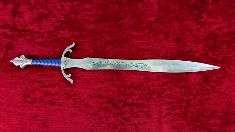 A medieval-style short sword with a silver-colored blade featuring blue floral engravings, a blue wrapped grip, and a silver guard, displayed horizontally on a textured red velvet background.