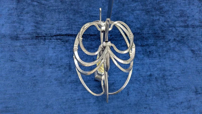 A silver metal cage-style guard, likely for fencing or equestrian use, displayed against a textured blue background.
