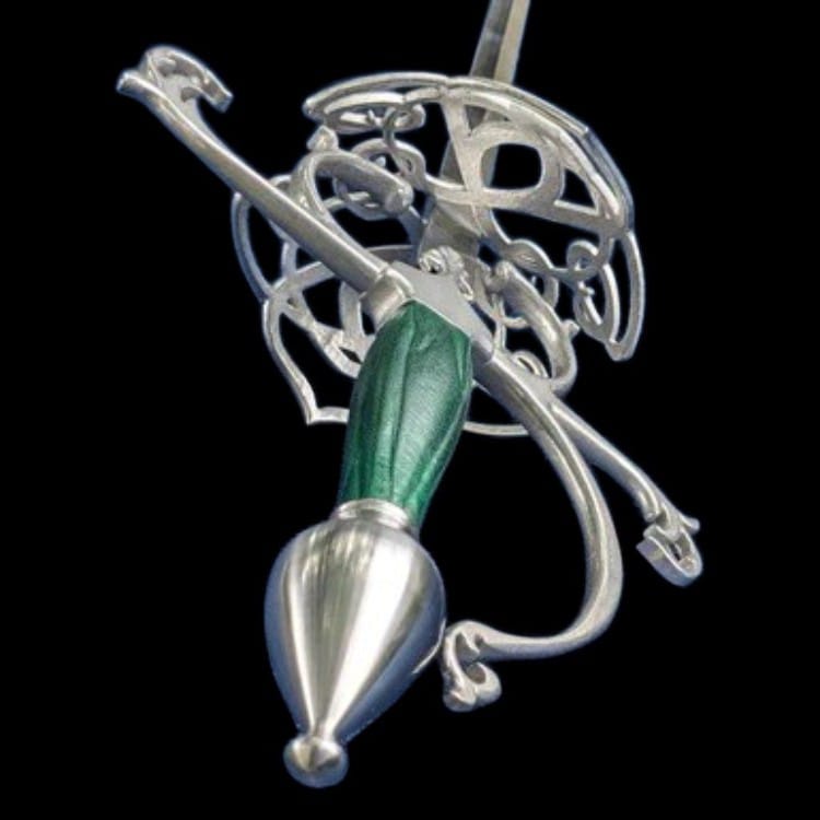 A silver-toned metal pendant or ornament featuring an intricate filigree design with a textured green handle and a polished teardrop-shaped end, shown against a solid black background.
