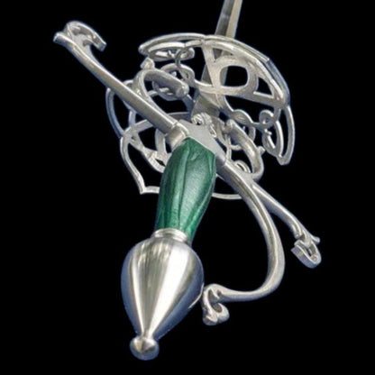 A silver-toned metal pendant or ornament featuring an intricate filigree design with a textured green handle and a polished teardrop-shaped end, shown against a solid black background.