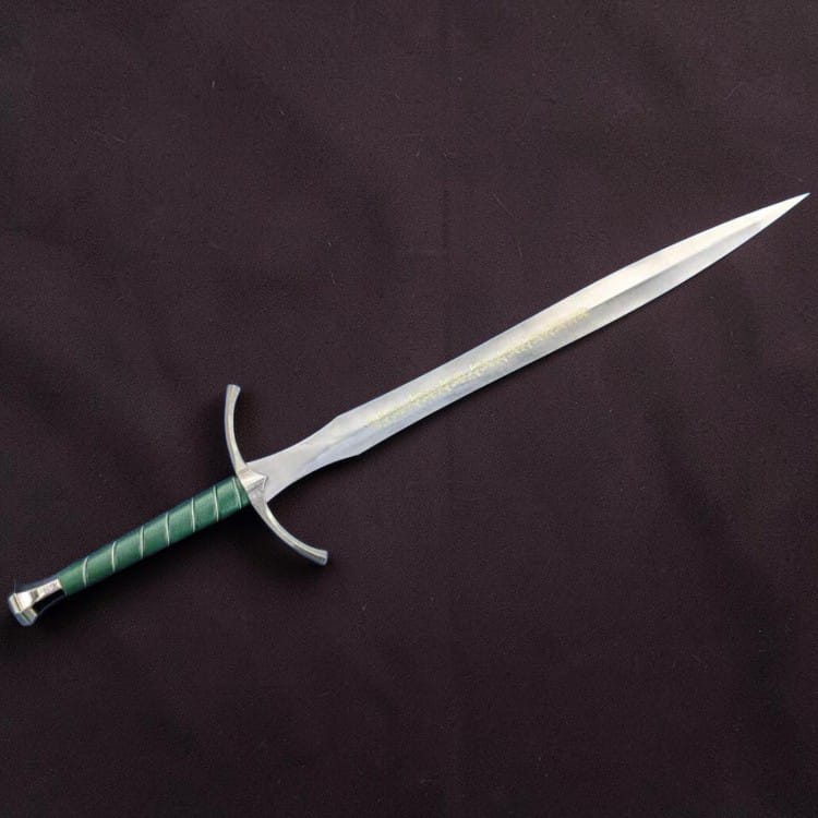 A fantasy-style sword with a silver blade, curved silver crossguard, and a green wrapped hilt, displayed diagonally on a dark textured fabric background.