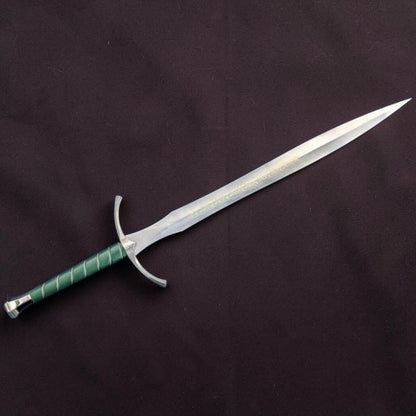 A fantasy-style sword with a silver blade, curved silver crossguard, and a green wrapped hilt, displayed diagonally on a dark textured fabric background.