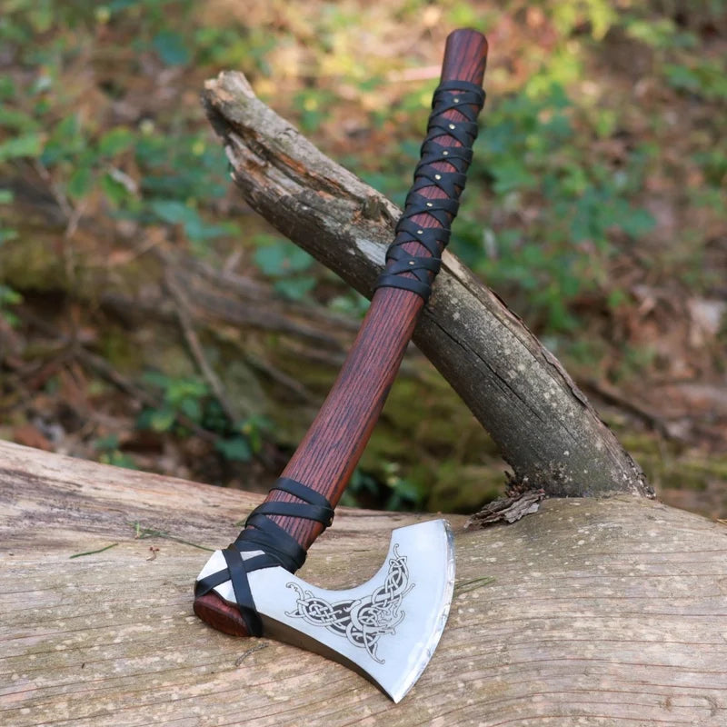 Viking-style axe with wooden handle and decorative blade on a wooden surface