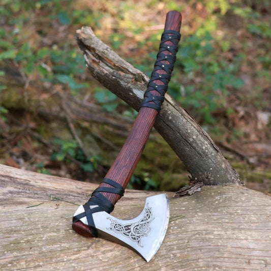 Viking-style axe with wooden handle and decorative blade on a wooden surface