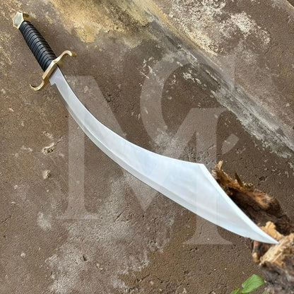 A curved sword with a black wrapped handle and gold guard, resting on a textured concrete surface.