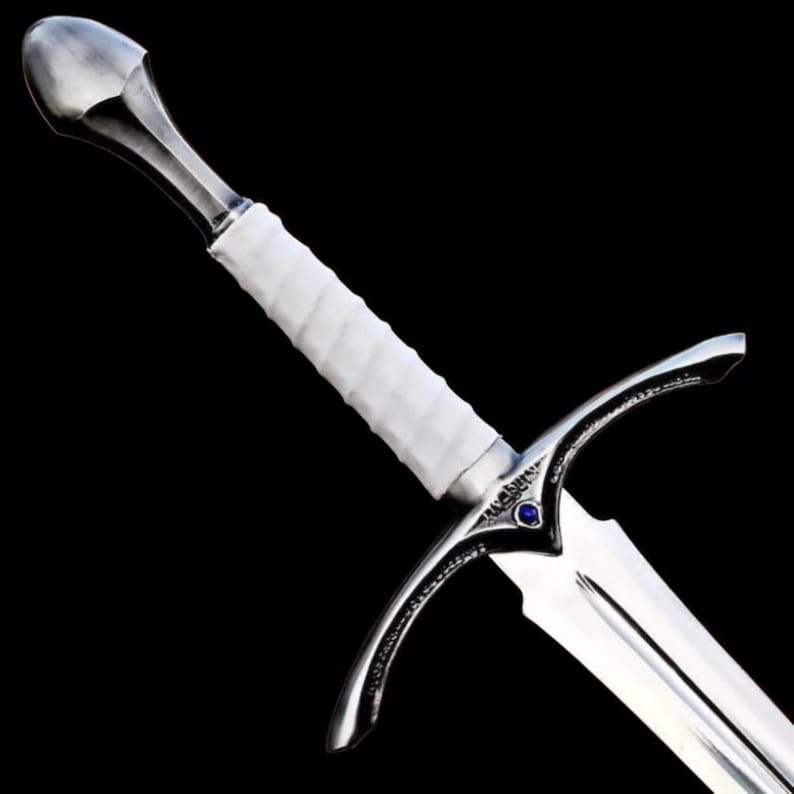Close up image of the handmade medieval knight longsword handle with white leather grip, decorative steel guard, and polished pommel