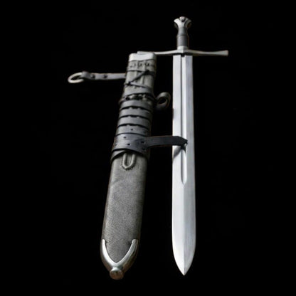 Medieval longsword displayed beside its leather scabbard showing the blade, crossguard, and handle
