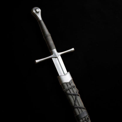 Medieval longsword with dark leather-wrapped handle and matching scabbard shown against a black background