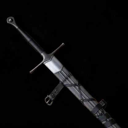 Medieval longsword partially sheathed in a dark leather scabbard against a black background